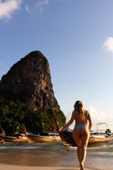 Happy woman on the beach in swimsuit with boats in the background