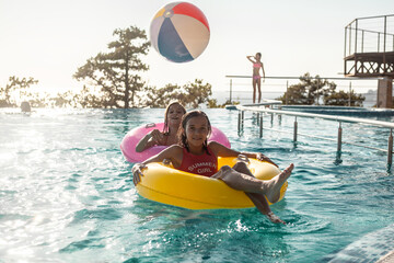 Children resting in swimming pool together. Kids swim, dive, leisure and playing infatable ball in pool at suumer vacation