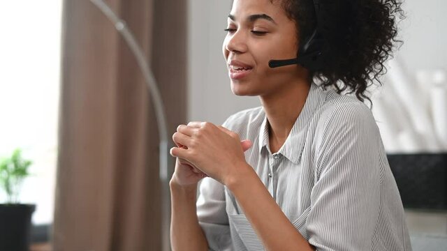 Close-up of an African businesswoman in a headset holding the microphone and takes a call, an attentive multiracial female customer service representative responding to the customer inquiry