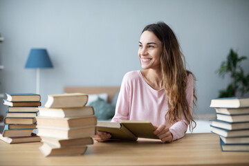 Girl student sitting at a table with a bunch of books, preparing for exams.