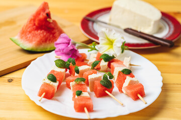 watermelon canapes with cheese sprinkled with mint on a plate