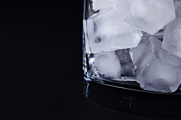 Ice cubes at the bottom of the glass close up on a black background with a copy space. High quality...