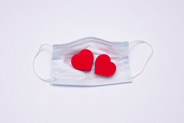 A medical mask and two red hearts.