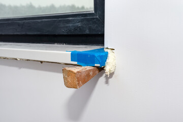 Newly installed white conglomerate window sill inside the room. Propped on a peg and filled with...