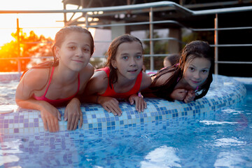 Children resting in swimming pool together. Kids swim, dive, leisure and playing infatable ball in...