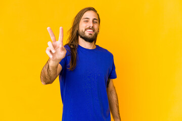 Young man with long hair look showing victory sign and smiling broadly.