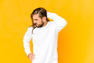 Young man with long hair look tired and very sleepy keeping hand on head.