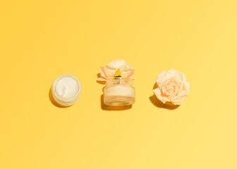 Natural skincare cosmetic Template with copy space Two glass bottles and rosebuds on yellow background  Flat lay photo