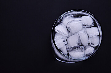 A glass full of drinking water with ice cubes view from above on a black background with a copy space. High quality photo