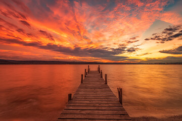 Fototapeta na wymiar Exciting colorful sunset view from the shore with a wooden pier