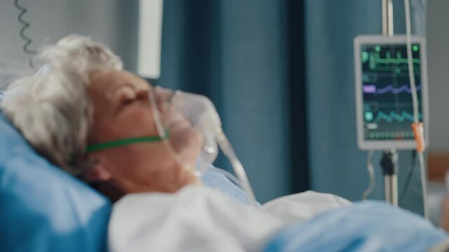 Hospital Ward: Portrait of Beautiful Elderly Woman Wearing Oxygen Mask Sleeping in Bed, Fully Recovering after Sickness and Successful Surgery
