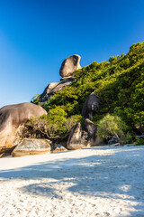 Beautiful, empty tropical sandy beach surrounded by lush green foliage and granite rocks (Ko Similan, Thailand)