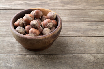 A group of hazelnuts in a bowl over wooden table with copy space
