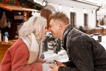 Happy young couple standing at table at open air Christmas market. Theme love holiday Valentines Day. Emotion romance of happiness and love.