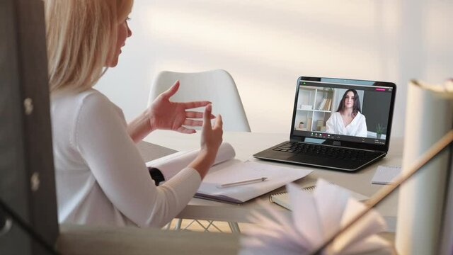 Online chat. Web conference. Corporate telework. Remote interview. Confident female leader discussing partnership with business woman on laptop screen at modern light home office.