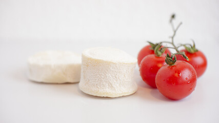 French handmade goat cheese 2 pieces and cherry tomato from local organic market. Close up, copy space.