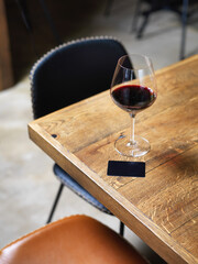 glass of wine on wooden table with wine card menu