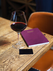 glass of wine on wooden table with wine card menu