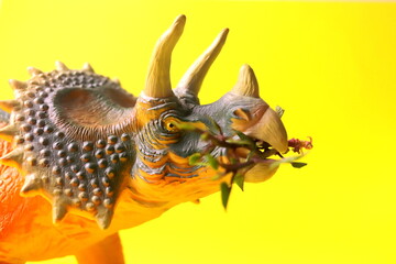 toy in the shape of a dinosaur on a yellow background close-up selective focus.