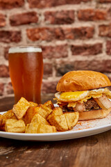 Tasty burger with fried egg and bacon served with potatoes.