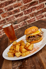 Tasty burger with fried egg and bacon served with potatoes.