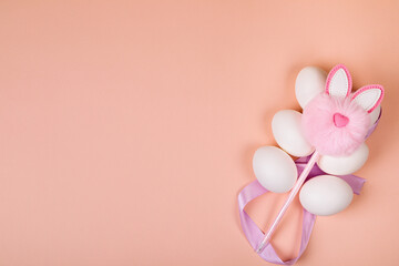 Fototapeta premium Easter. White eggs with an artificial rabbit on a uniform background.