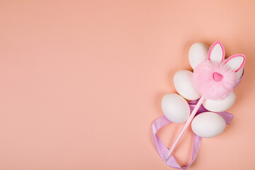 Easter. White eggs with an artificial rabbit on a uniform background.