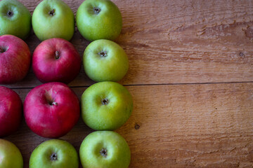 Green and red apples stand on a wooden surface