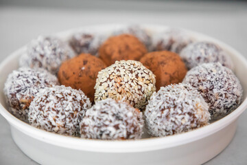 Handmade coconut snow balls made from dates, almond and coconut truffles on grey surface, healthy eating cocept
