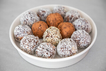 Handmade coconut snow balls made from dates, almond and coconut truffles on grey surface, healthy eating cocept