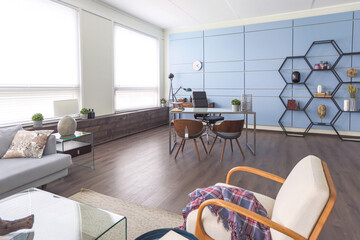 Modern trendy creative design of a personal studio office with a seating area in the style of minimalism in blue and beige colors with large windows and daylight