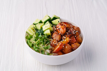 Bowl with rice, chicken, pineapple, cucumber and pea sprouts on a white wooden background