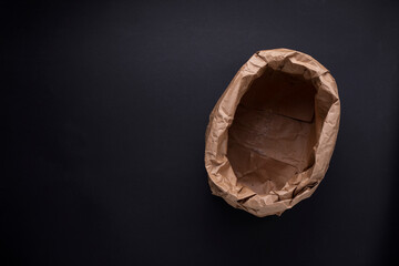 Empty paper bag on dark background, copy space. Bio degradable, eco friendly waste