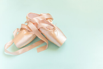 New pastel beige ballet shoes with satin ribbon isolated on blue background. Ballerina classical...