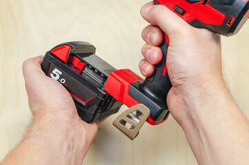 Electric screwdriver on a battery in the hands of a carpenter. Male hands are holding an electric...