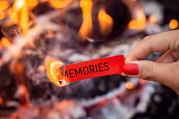 Burning paper with inscription Memories. Concept of erasing negative memories, living through them,...