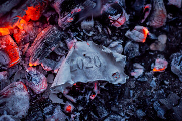 Burnt paper with inscription 2020 in ashes of the fire. End of difficult 2020 year