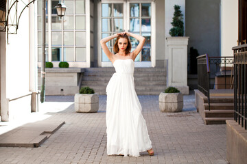 Obraz premium Full length portrait of beautiful model woman with long legs wearing white dress