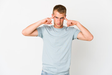 Fototapeta premium Young caucasian handsome man focused on a task, keeping forefingers pointing head.