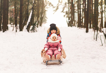 Fototapeta premium Little boy takes his little sister on a sled in winter.