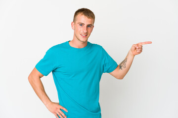 Young caucasian handsome man smiling cheerfully pointing with forefinger away.