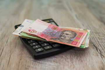 hryvnia and calculator on a wooden background.