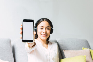 Pretty woman from blurred background showing cellphone with white screen