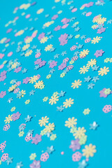 Festive blue background with colorful flowers. Multi-colored small artificial flowers. Flat lay, top view.
