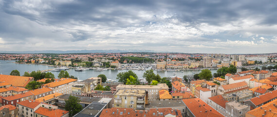 Fototapeta na wymiar Large panorama with drone or birds eye view on orange tiled roofs and cityscape of Zadar. Bay or marina with moored yachts and boats, Croatia