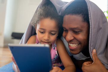Father and daughter using digital tablet at home.