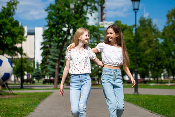 Fototapeta premium Two happy girlfriends teenagers are walking in the summer park.