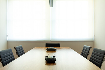 sala de reuniões com mesa de madeira e cadeiras pretas com janela ao fundo