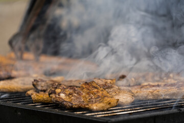 Meat and sausages being grilled with heavy smok © Sorin Narcis Gheorghita/Wirestock