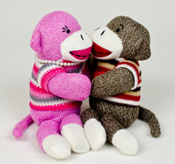 A pair of sock monkeys holding eachother
